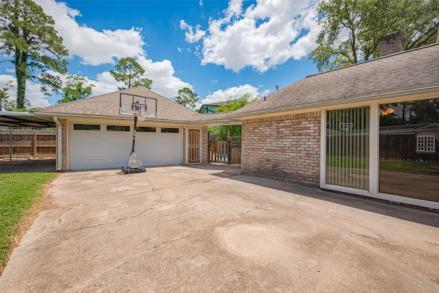 view of side of property featuring fence, a garage, driveway, and an outbuilding