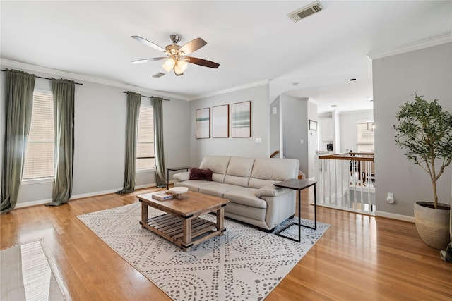 living area with baseboards, visible vents, light wood-style floors, and ceiling fan