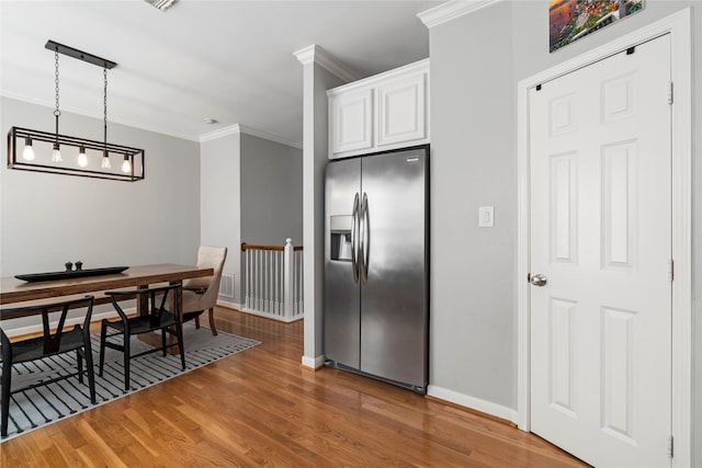 kitchen with white cabinets, wood finished floors, crown molding, baseboards, and stainless steel refrigerator with ice dispenser