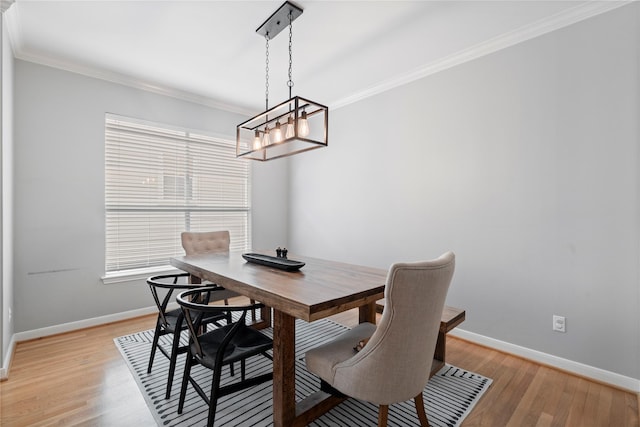 dining space with baseboards, an inviting chandelier, light wood-style floors, and crown molding