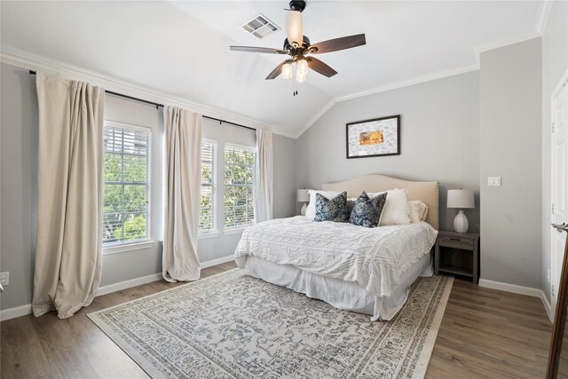 bedroom with vaulted ceiling, visible vents, wood finished floors, crown molding, and baseboards