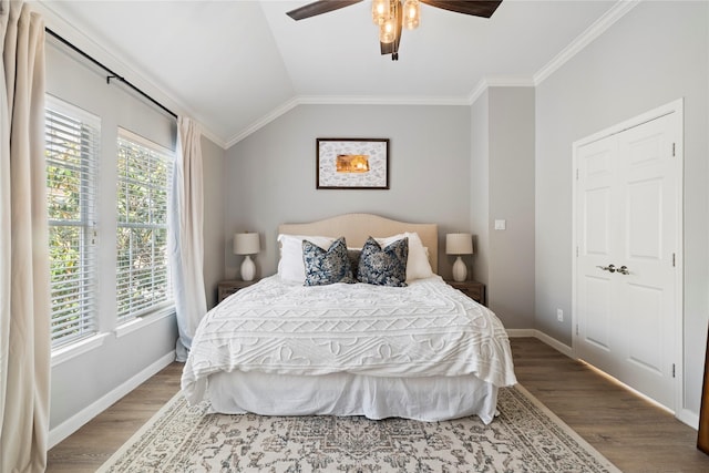 bedroom featuring lofted ceiling, baseboards, wood finished floors, and ornamental molding