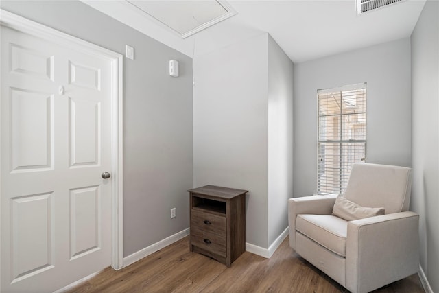 sitting room with attic access, wood finished floors, visible vents, and baseboards