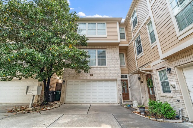 multi unit property with brick siding, driveway, and an attached garage