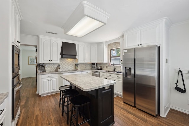 310 Yorkshire Ln, Port Neches, TX 77651 - kitchen with stainless steel appliances, a sink, visible vents, custom exhaust hood, and white cabinetry