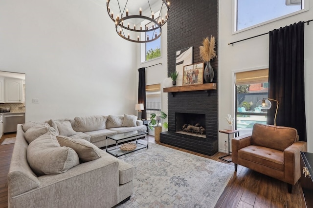 310 Yorkshire Ln, Port Neches, TX 77651 - living room featuring a brick fireplace, hardwood / wood-style floors, a high ceiling, and a notable chandelier