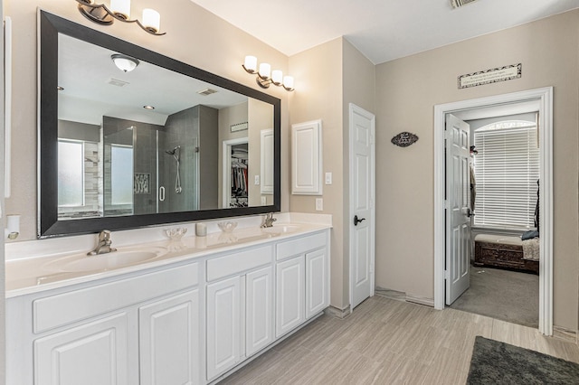 bathroom featuring a stall shower, double vanity, a sink, and visible vents