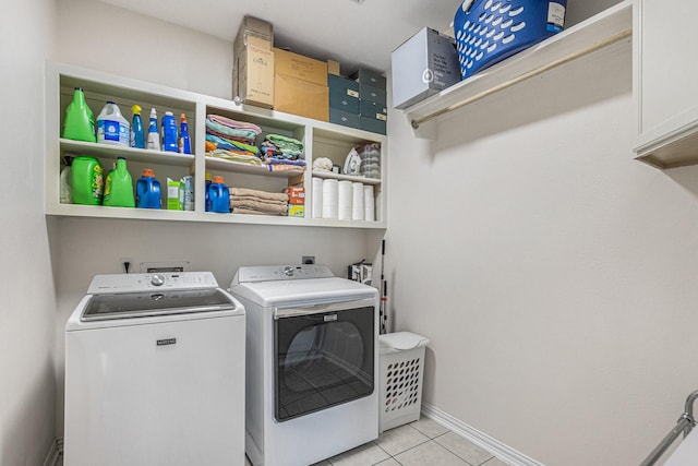 laundry room featuring light tile patterned floors, separate washer and dryer, baseboards, and cabinet space