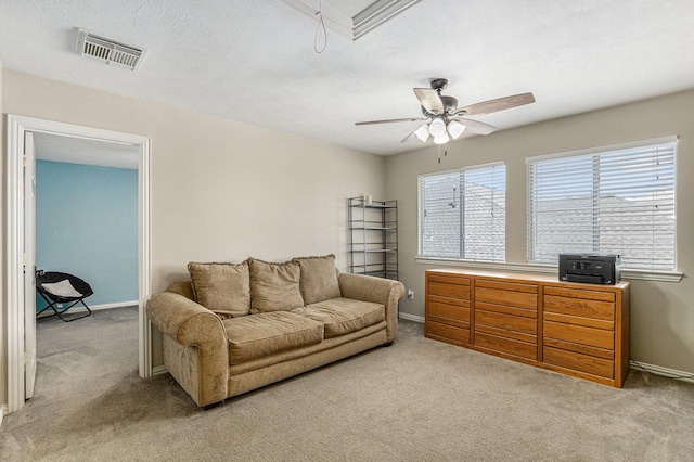 living area with light carpet, baseboards, a ceiling fan, and visible vents