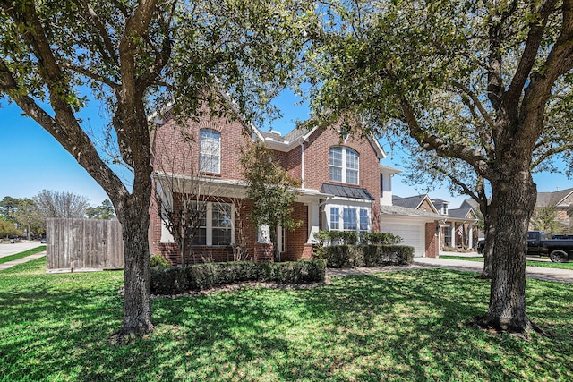 traditional home with concrete driveway, a front lawn, brick siding, a garage, and a standing seam roof