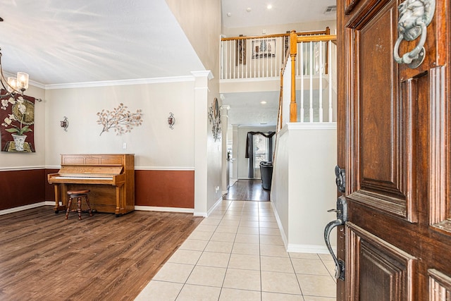 entrance foyer with a notable chandelier, light wood-type flooring, baseboards, crown molding, and visible vents