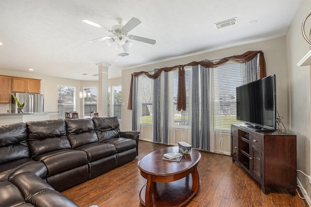 living room featuring visible vents, dark wood-style floors, ceiling fan, and decorative columns