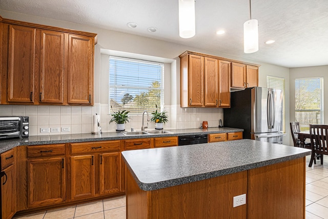 kitchen with dark countertops, dishwasher, freestanding refrigerator, and a sink