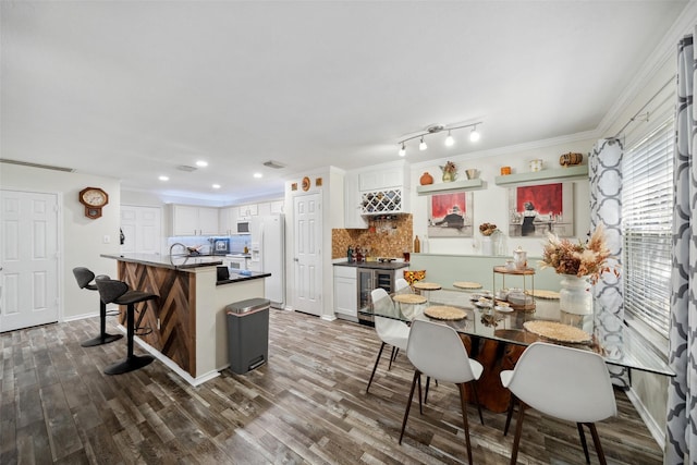 38 Wineberry Pl, The Woodlands, TX 77382 - dining space with wine cooler, bar, dark wood finished floors, recessed lighting, and crown molding
