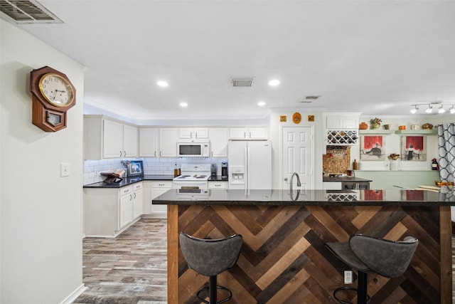 38 Wineberry Pl, The Woodlands, TX 77382 - kitchen featuring white appliances, a breakfast bar, dark countertops, tasteful backsplash, and recessed lighting