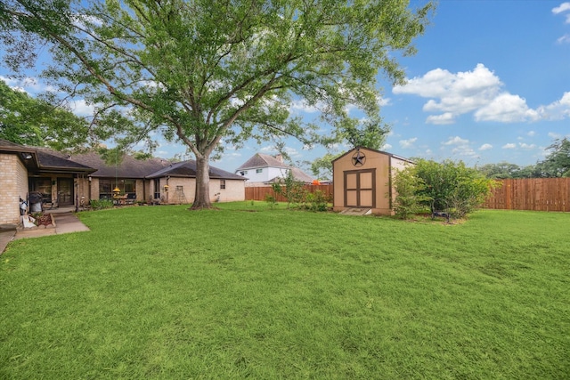 view of yard with an outdoor structure, a shed, a fenced backyard, and a patio area