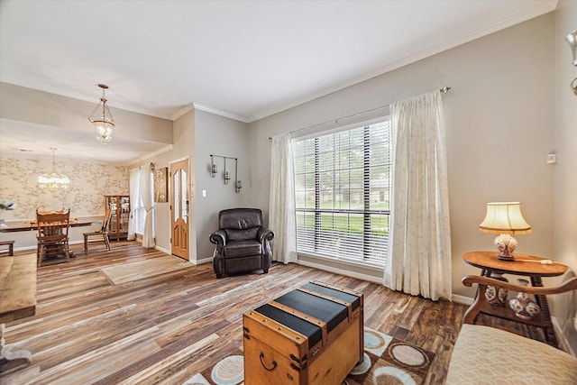 living room with baseboards, ornamental molding, wood finished floors, and a chandelier