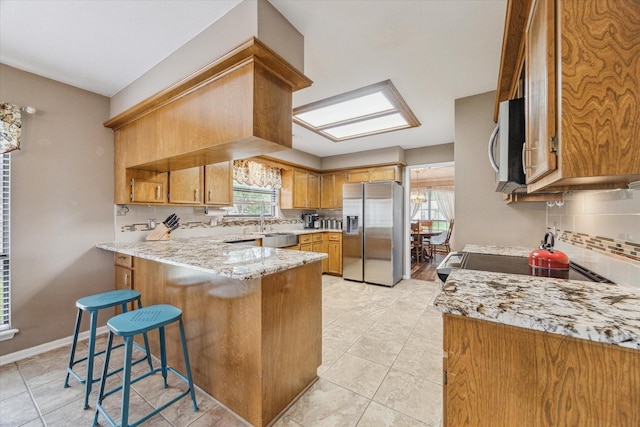 kitchen with backsplash, stainless steel appliances, a peninsula, and light tile patterned flooring