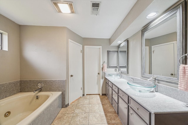 bathroom featuring double vanity, visible vents, a sink, and a garden tub
