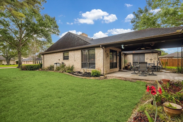 back of house with a chimney, a patio area, brick siding, fence, and a yard