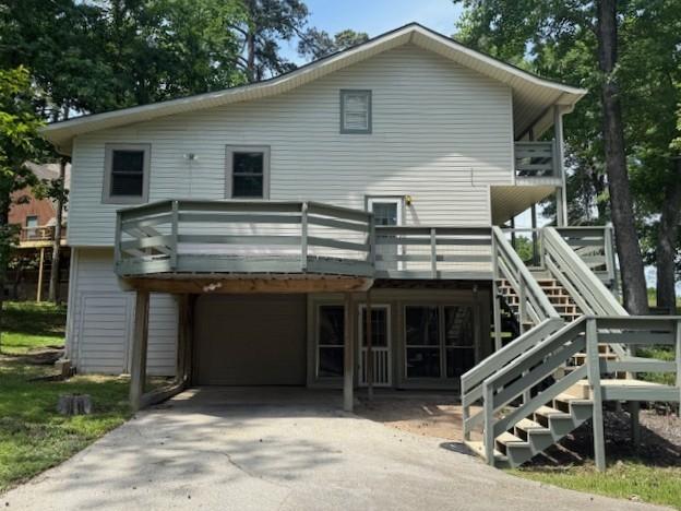 11 Ridgeway St, Coldspring, TX 77331 - rear view of property featuring a garage, concrete driveway, stairway, and a deck