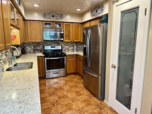 1814 Cliffdale Dr, Missouri City, TX 77489 - kitchen with brown cabinetry, backsplash, appliances with stainless steel finishes, and a sink