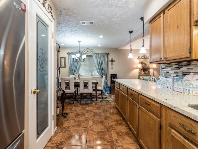 1814 Cliffdale Dr, Missouri City, TX 77489 - kitchen with brown cabinets, backsplash, visible vents, freestanding refrigerator, and a chandelier
