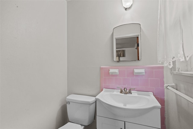 bathroom featuring tile walls, toilet, vanity, and a wainscoted wall