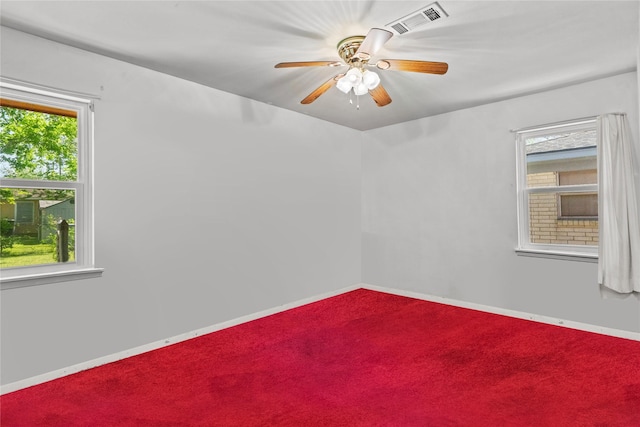 spare room with carpet floors, visible vents, a ceiling fan, and baseboards