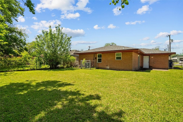 back of property featuring brick siding, a yard, fence, and a gate