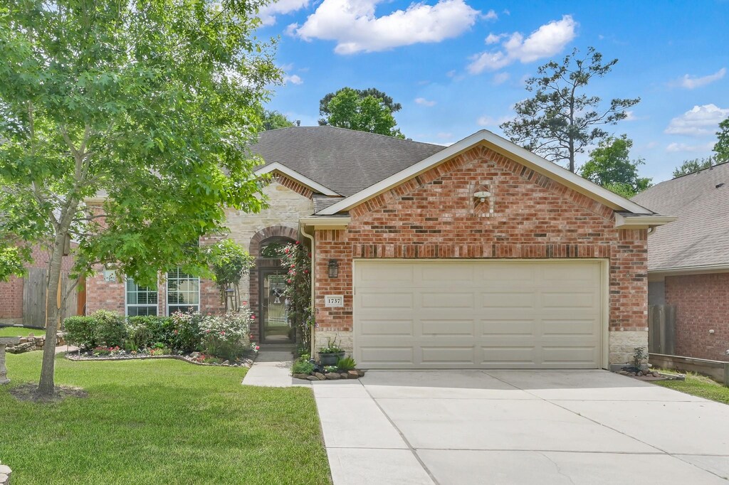 1737 Round Oak Ln, Conroe, TX 77304 - traditional home with a front lawn, driveway, stone siding, brick siding, and a garage