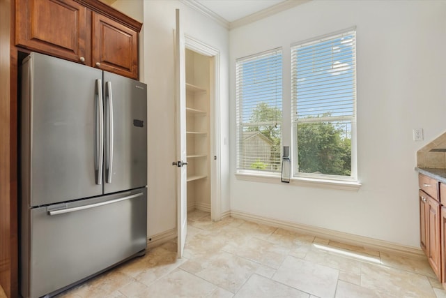 91 Sidney St, Houston, TX 77003 - kitchen featuring brown cabinets, baseboards, crown molding, and freestanding refrigerator