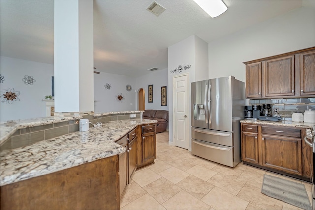 606 Sea Anchor Way, Crosby, TX 77532 - kitchen with arched walkways, stainless steel fridge, visible vents, decorative backsplash, and light stone countertops