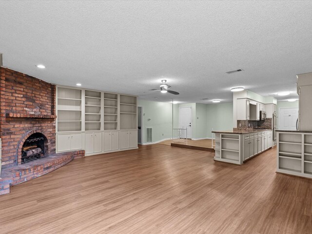 unfurnished living room featuring a ceiling fan, a textured ceiling, and light wood-type flooring
