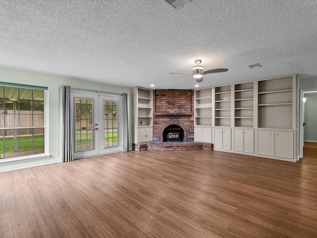 unfurnished living room with a ceiling fan, a textured ceiling, french doors, and wood finished floors