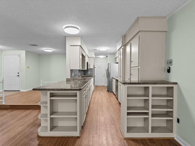 kitchen with visible vents, open shelves, light wood finished floors, and freestanding refrigerator