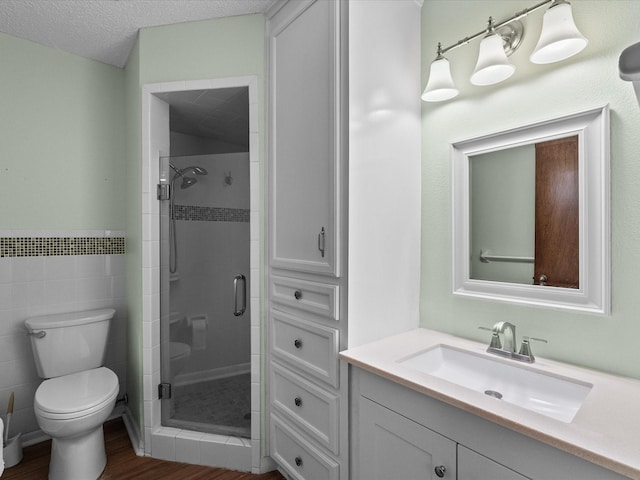 full bathroom with tile walls, a shower stall, toilet, and wood finished floors