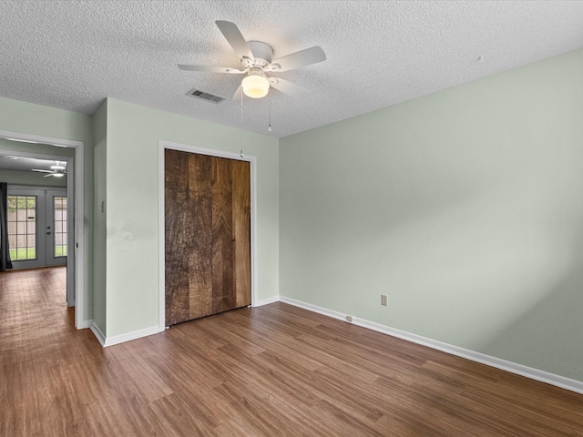 unfurnished bedroom featuring a textured ceiling, baseboards, wood finished floors, visible vents, and a closet
