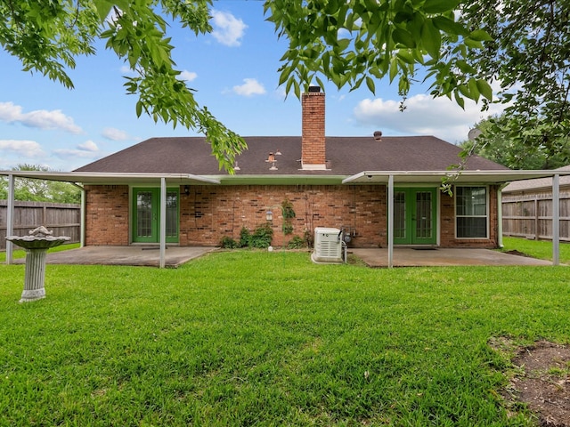 rear view of house with fence, a chimney, french doors, a patio, and a lawn