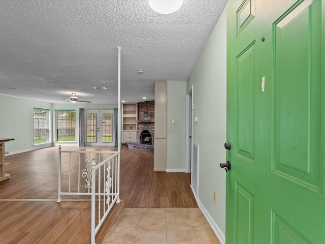 entrance foyer featuring french doors, a textured ceiling, wood finished floors, and a fireplace