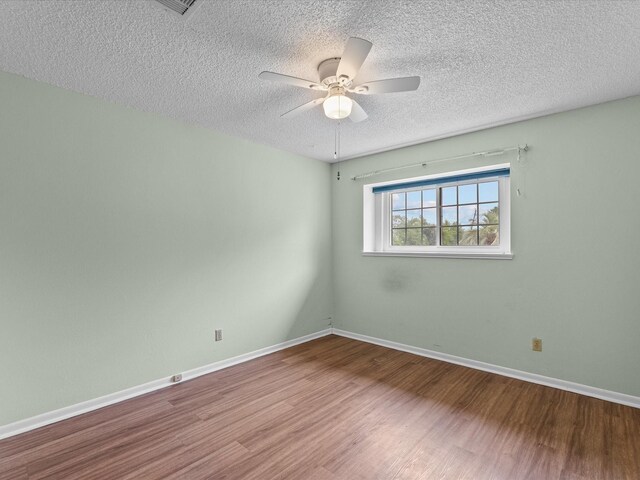 spare room with baseboards, ceiling fan, a textured ceiling, and wood finished floors