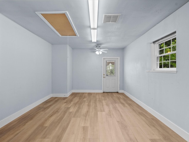 empty room featuring visible vents, attic access, light wood-style flooring, and a healthy amount of sunlight