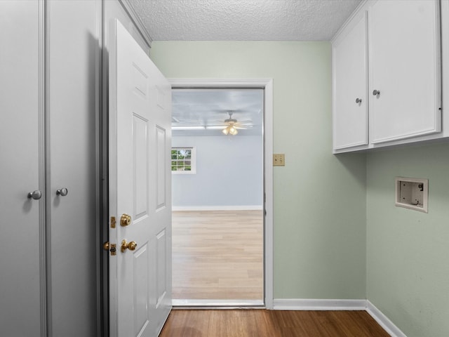 clothes washing area with baseboards, cabinet space, wood finished floors, and washer hookup