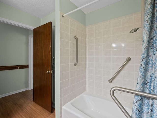 bathroom featuring a textured ceiling, shower / bathtub combination with curtain, and wood finished floors