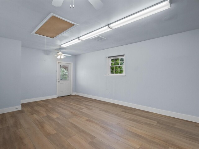 unfurnished room featuring ceiling fan, attic access, and wood finished floors