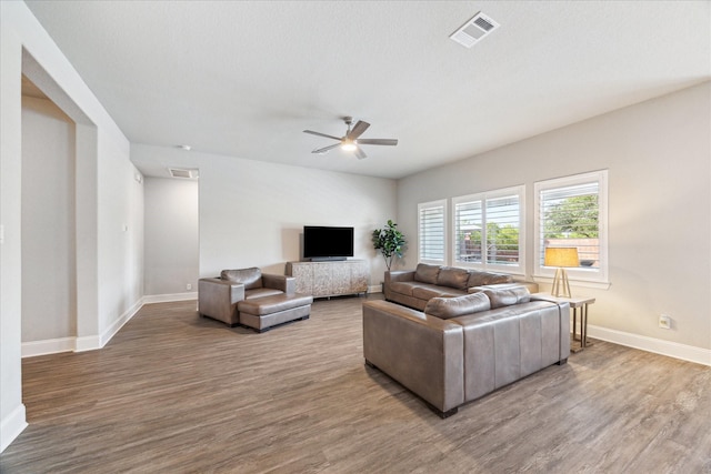living area featuring baseboards, a ceiling fan, wood finished floors, and visible vents