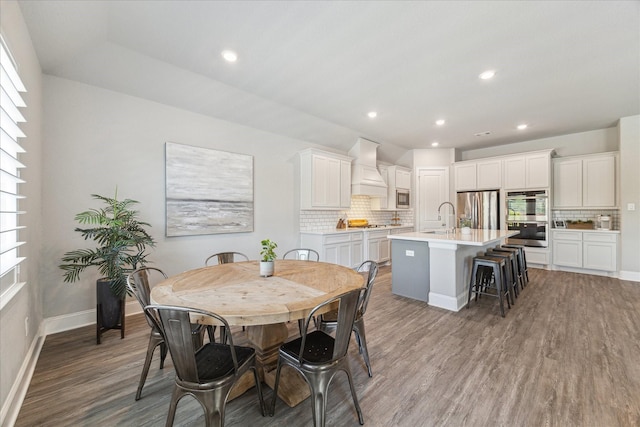 dining room with baseboards, wood finished floors, and recessed lighting