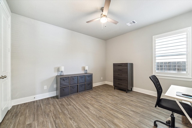 office space with baseboards, a ceiling fan, wood finished floors, and visible vents