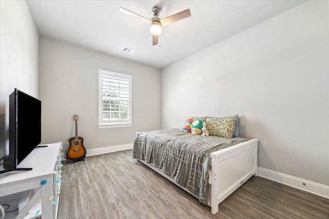 bedroom featuring baseboards, wood finished floors, visible vents, and ceiling fan