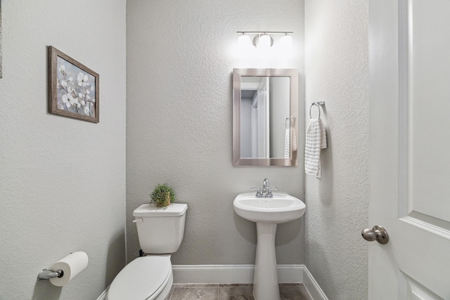 half bathroom with toilet, baseboards, and a sink